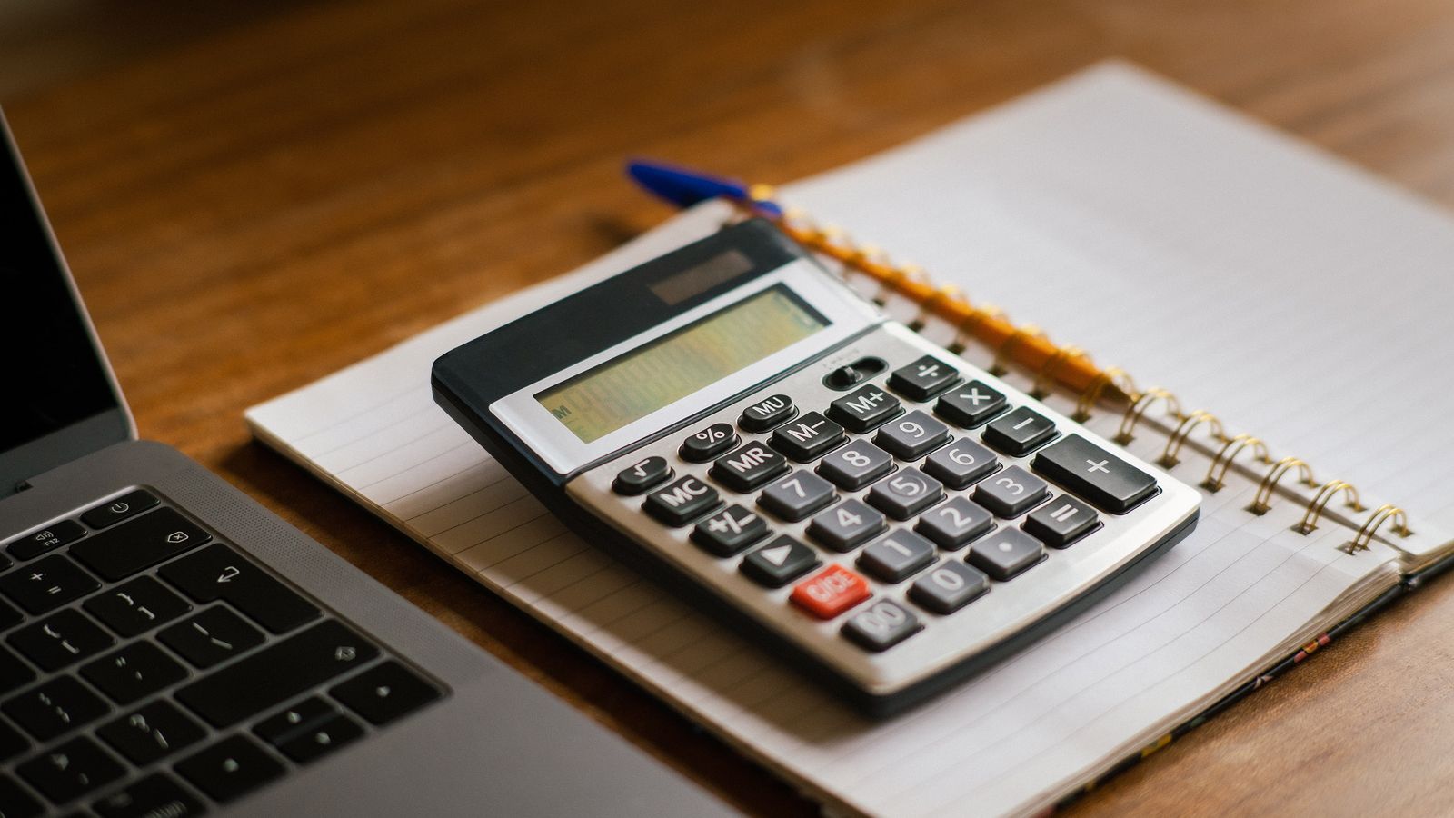 Calculadora, caderno e notebook sobre a mesa