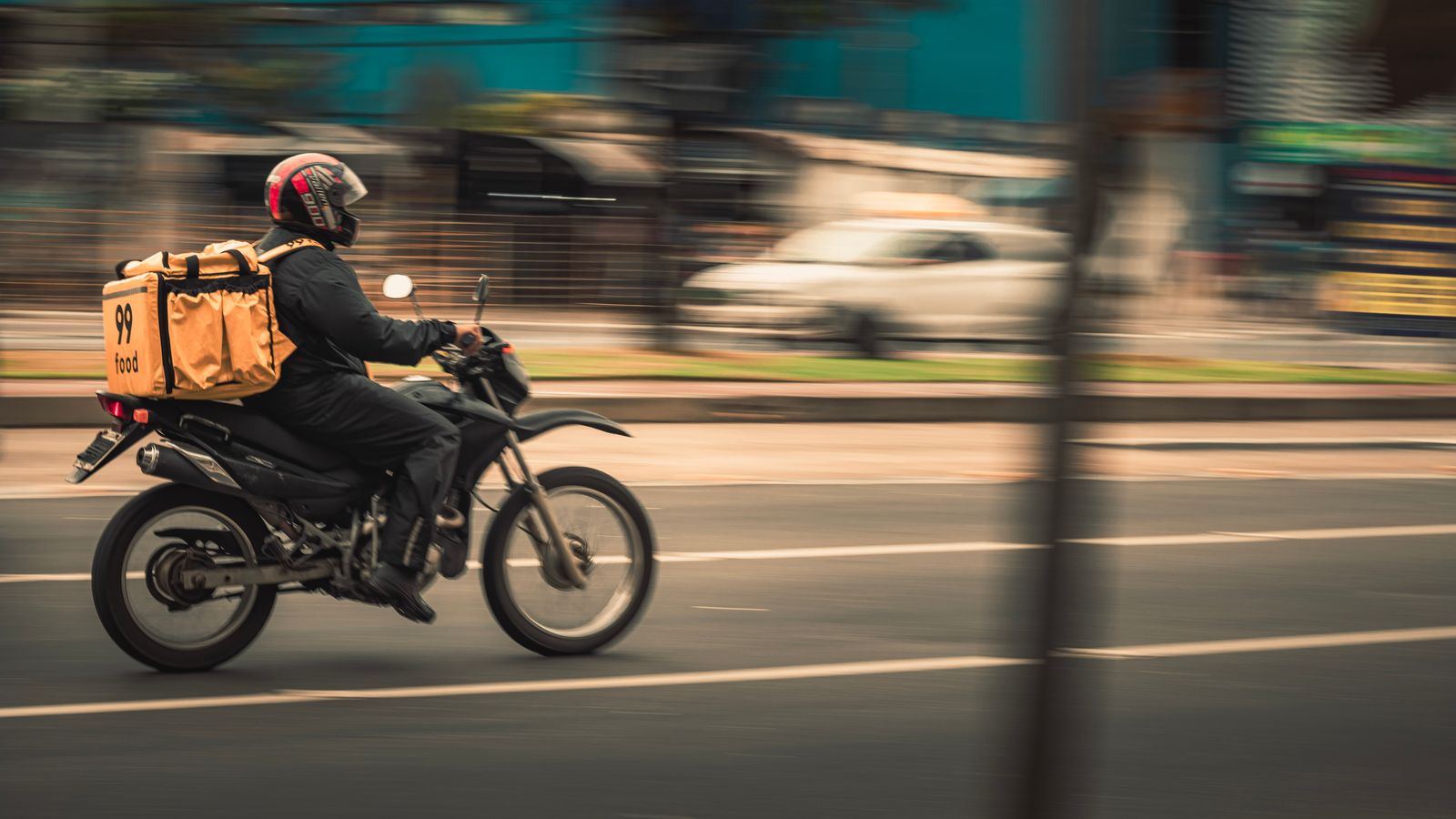 Entregador de moto com a bag de entrega na rua