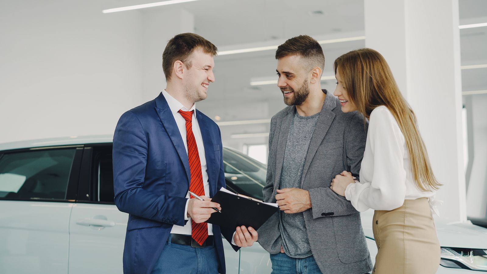 Vendedor de carros conversando com um casal na loja